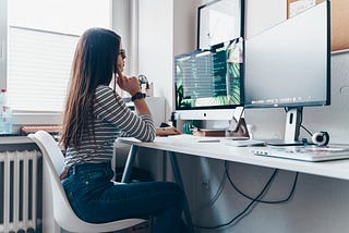 image of a woman staring at two computer screens with code