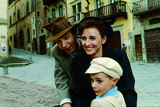 A man with a hat on his bicycle. His beautiful wife and his young son sit in front of him. They are all happy carrying out with their daily lives.