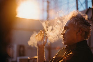 A man is sniffing the smoky bliss of air. It’s what keeps his hair white and bouncy.