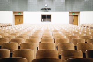 Empty university lecture hall, looking onto rows of chairs