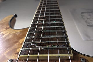 A picture looking down a guitar neck with highly polished frets and fresh strings