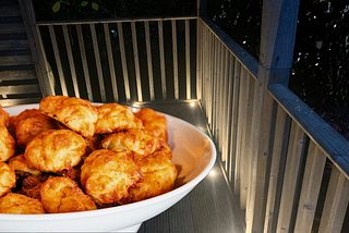 plate of cheese puffs in foreground, porch in evening light with light rain falling in background