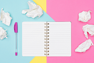 Notepad, pen, and crumpled paper against a pastel background — The Ultimate List of My Favorite Writing Tools