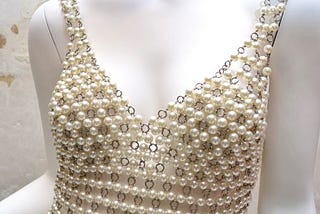 White mannequin wearing chain link and pearl dress.