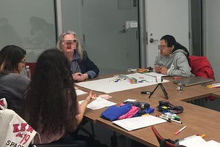 A picture taken at the co-design workshop wherein 3 students are seen working closely with a person with dementia.