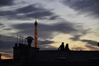 Couple sitting on a roof in Paris at Sunset.