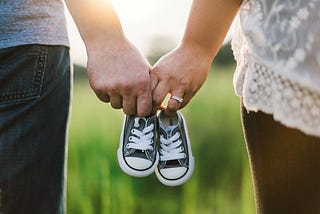 Couple linked by holding baby shoes