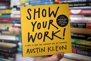 Photo of the book being held in front of a books rack