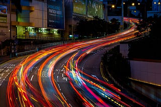 Time lapse of a busy city highway at night, the blur of headlights signifying the speed of urban life.