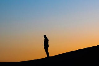 Man standing under blue sky at sunset