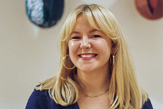 A head and shoulders picture of Kryssie, who is wearing a dark blue top and smiling into the camera.