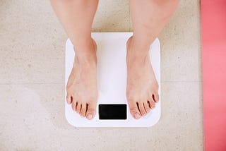 A photo of a pair of feet standing on a weighing scale.