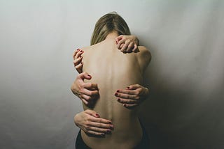 A woman with hands all over her naked back