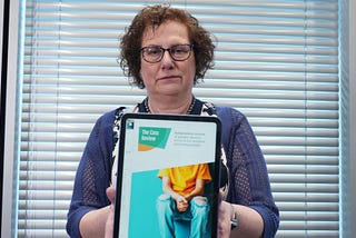 Hilary Cass holding up a tablet showing the front page of The Cass Report