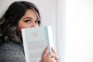 Woman holds book up to her face