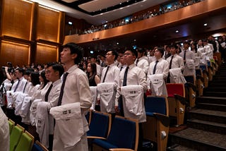 Students stand holding their white coats