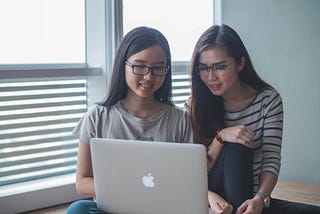 Two young women working in front of a computer