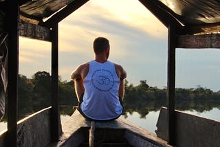 Man sitting alone on a boat gazing into a sunset