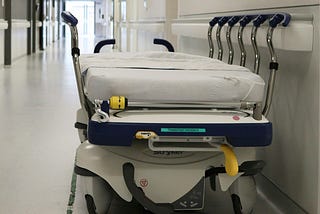 A hosptial gurney sitting empty in a hallway.