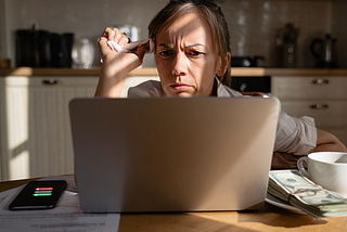 Tense woman reading content on a laptop in a kitchen.