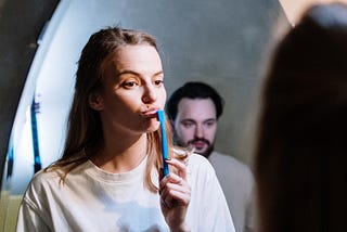 A woman with a toothbrush staring in the mirror