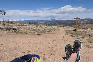 daytime scene overlooking the Colorado mountains with shoes and a backpack in frame