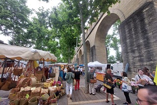 A lively French market underneath an acqueduct.
