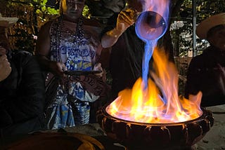 Ceramic container of burning alcohol with man pouring ladle of alcohol, that is burning blue, back into the pot.