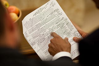 A picture of President Obama reviewing his handwritten edits to a printed draft of a speech.