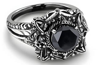 Ring with a black gemstone etched with various silver, grey and black details, and few smaller clear gemstones.