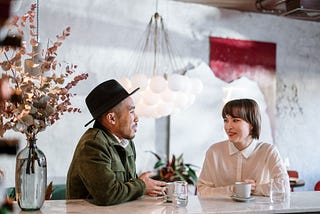 A man and a woman in conversation over a cup of coffee.