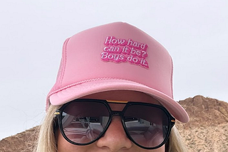 Pink hat wotk ‘how hard can it be? Boys do it’ written on it