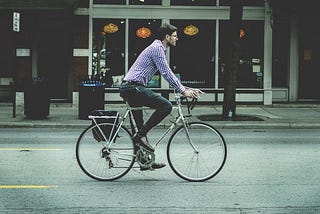 Man riding vintage bike down the city street.