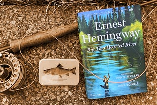 Ernest Hemingway book shown with fly rod and a small fly box.