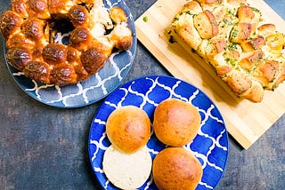 A table laid with hamburger buns, sweet monkey bread, and savory monkey bread