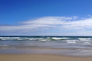 picture of beach with waves and blue sky
