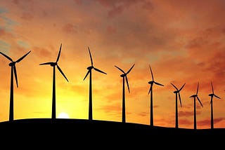 wind turbines in front of a sun set