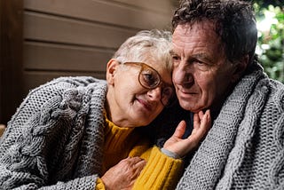 Portrait of senior couple sitting in the evening on terrace, hugging.