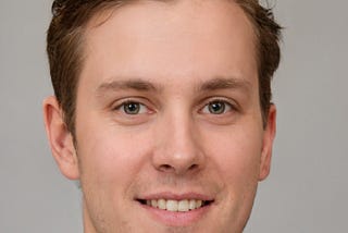 Corey Shader, a 22-year-old man, light eyes, dark blonde hair, smiles into the camera. Friendly face.