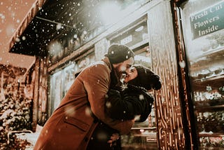 a couple in love kissing in a snowy white Christmas scenery