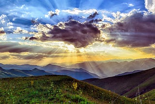 Stunning sunrise in blue and gold with sun peering behind grey cloud