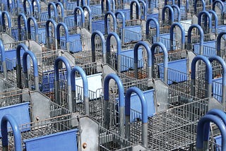 Hundreds of shopping carts lined up organized, blue plastic covering gray metal. A consumer’s heaven.