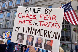 A protester holds up a handmade sign, “Rule By Chaos, Fear, Hate, and Threats is UNAMERICAN.” Photos below this are of Adolph Hitler, Donald Trump, Vladimir Putin, and Xi Jinping. (Photo by author.)