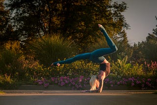 Woman balancing in a yoga pose with flowers in the background