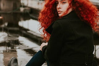Red haired woman sitting on the ground.