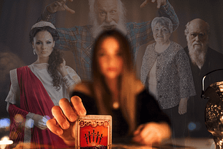 Blurred tarot reader showing an in-focus tarot card to the camera, with spirits standing behind her. Left to right: spirits behind her are a woman in a red robe and a tiara, an old man with his hands up, an old woman, and a sage old man. Who Do You Think You’re Talking To? Why you should question the source of tarot messages by Gem Blackthorn