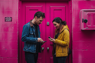 A man and a woman standing across from each other while holding their phones.