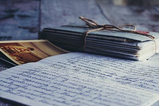 A stack of letters bound with string. One letter open with a photo under it.