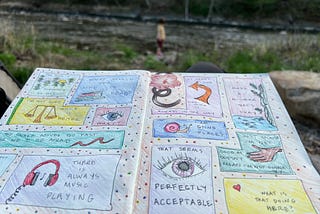 A notebook covered in colorful doodles, background of a river