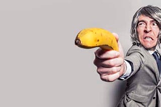 Executive holding a banana as if it were a gun